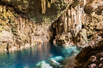 beautiful natural pool of crystal clear water formed in a rocky cave with stalagmites and stalagmites