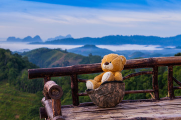 a doll bear sitting on bamboo chair beside military dress on hilltop