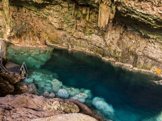beautiful natural pool of crystal clear water formed in a rocky cave with stalagmites and stalagmites
