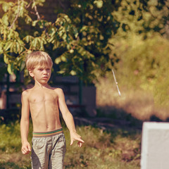 Concentrated sporty young boy training with throwing knife, image with toning and square aspect...
