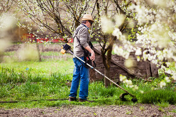 man cutting grass in garden with the weed trimmer