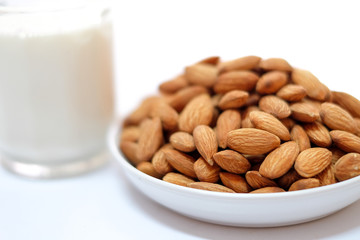 Almond milk in glass with almonds on white background