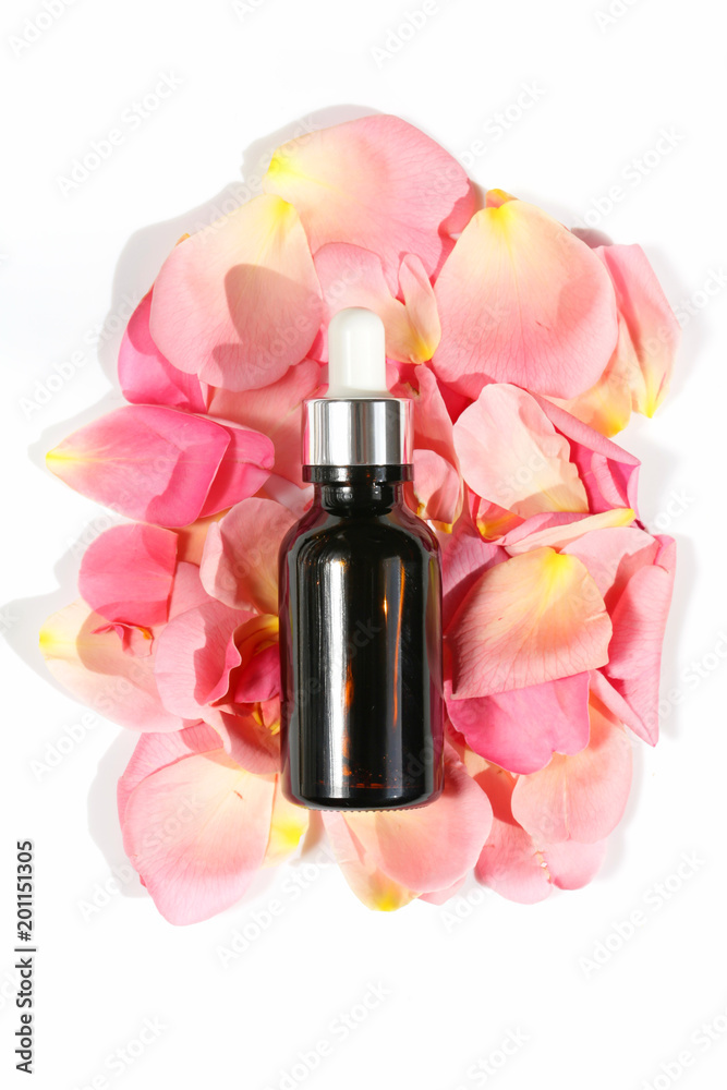 Wall mural rose petals extract. Serum for face skin with rose petals extract in a brown glass bottle and petals of a pale pink rose on a white background. Organic Natural Pure Cosmetics 