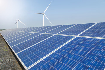      Rows array of  polycrystalline silicon solar panels and wind turbines generating electricity in hybrid power plant systems station 