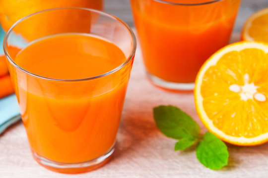 Glasses with carrot juice, carrot, sliced orange and mint leaf 