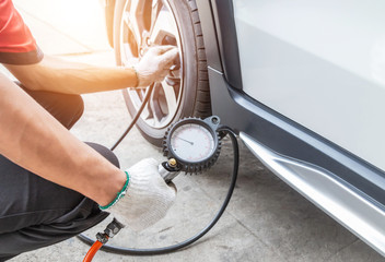 Close up mechanic inflating tire and checking air pressure with gauge pressure in service station          