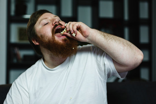 Close-up of a fat man looking ugly while he eats pop-corn