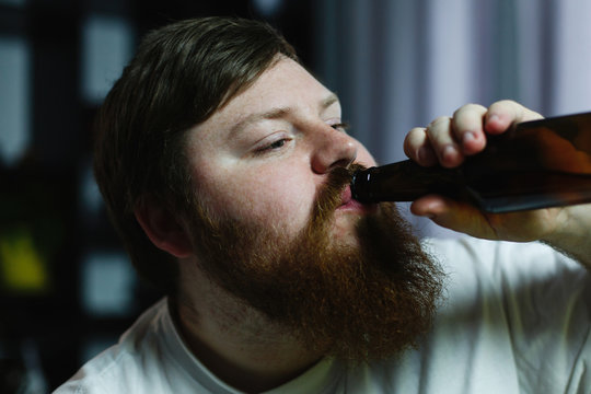 Close-up of a fat man looking ugly while he drinks beer