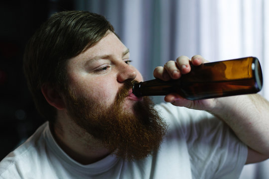 Close-up of a fat man looking ugly while he drinks beer