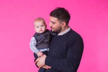 happy father with a baby son isolated on a pink background
