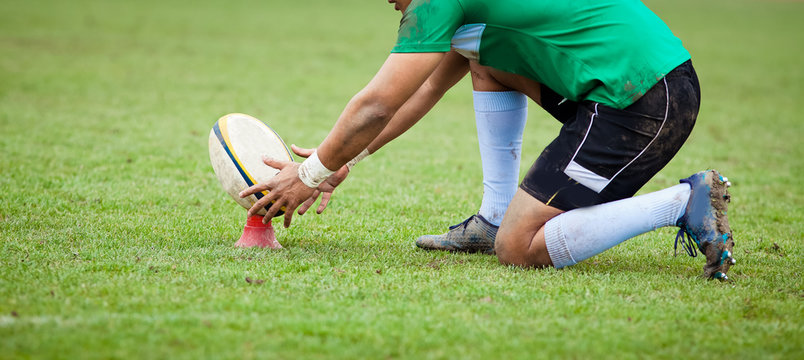 rugby player preparing to kick the oval ball during game