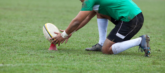 rugby player preparing to kick the oval ball during game