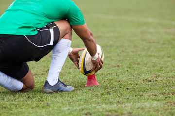 rugby player preparing to kick the oval ball during game