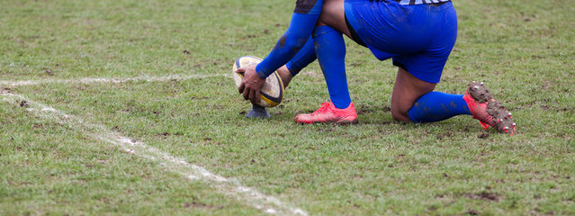 rugby player preparing to kick the oval ball during game