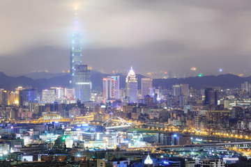Obraz premium Aerial view of Taipei City with Taipei 101 tower standing tall into clouds, and Keelung River and skyscrapers in downtown area in evening twilight ~ Scenery of foggy Taipei City with polluted hazy air