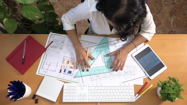 Female architect drawing building plan with graphic tablet correcting measures.  Caucasian interior designer planning apartment layout at computer. Woman drawing restoration flat using digital devices