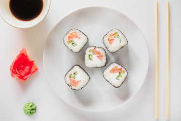 Roll of sushi on a plate, Sushi roll on a tablet on the table restaurant / eating sushi roll using chopsticks, white background, Sushi roll and hand with chopsticks. Japanese food.