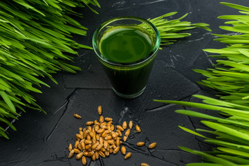 Green organic wheat grass drink over dark wood background,top view ,young grass stage.