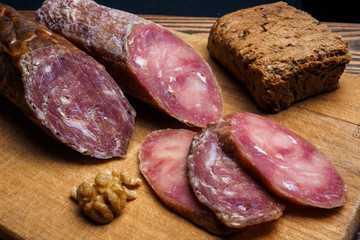 Smoked salami on a old wooden table. Sausages with rosemary , garlic and pepper. typical italian salami.