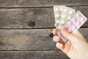 Medicine in tablet package in hand isolated on wooden background, pills in blister. copy space, template.