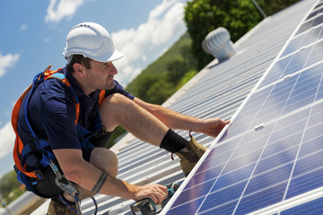 Solar panel technician with drill installing solar panels