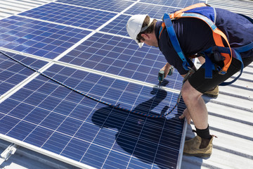 Solar panel technician with drill installing solar panels