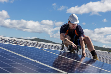 Solar panel technician with drill installing solar panels