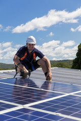 Solar panel technician with drill installing solar panels