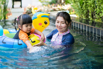 mother training daughter swimming in swimming pool