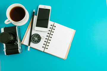 Creative flat lay photo of workspace desk with coffee, blank notebook, smartphone and film camera with copy space background, minimal styled