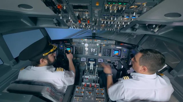 Two pilots turn the plane in a flight simulator.