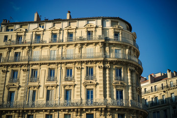 Fototapeta na wymiar Old times building with tall windows and balconies on sunset in Marseille, France. March 2018