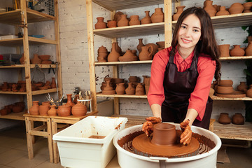 beautiful potter girl molds from clay pot in mastre. a woman works with clay on a potter's wheel. clay pot in the hands of a master