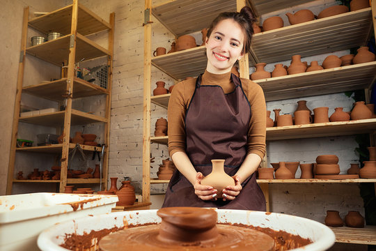a young and cheerful woman sculpts from clay. The potter works in a pottery workshop with clay. the concept of pottery mastery and creativity