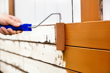 Mann lackiert Holzbretter mit braunem Lack
