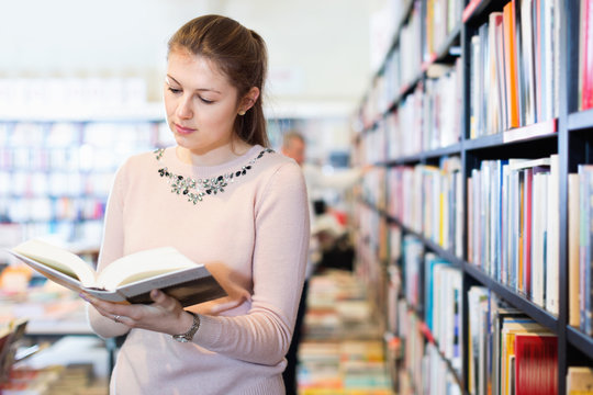 Young woman browsing inside of books while visiting public library