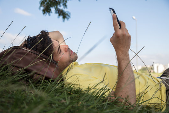Man resting in grass using mobile phone