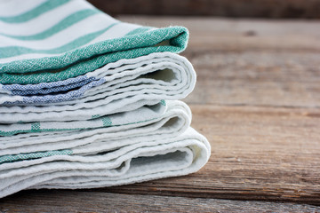 Clean washed kitchen towels stacked on a wooden table, copy space