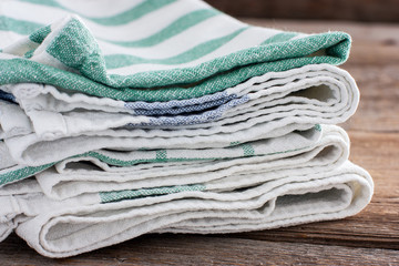 Clean washed kitchen towels stacked on a wooden table, copy space