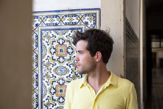 Man Looking Outside Against Wall With Mosaic Tiles