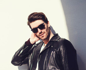 Sexy gorgeous stylish man in leather jacket. Charming man with sunglasses.