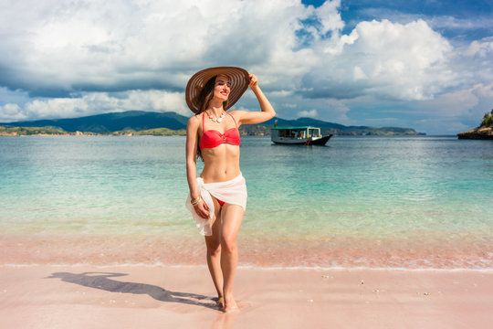Fashionable young woman with a perfect body smiling while posing outdoors during summer vacation at Pink Beach, pink, in Komodo Island, Indonesia 
