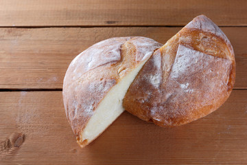 Sliced bread on a wooden background, two halves of wheat bread from a plate on pine boards, French dough for a designer, copy space, rustic style, wooden background, art