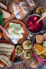 Traditional food in the Ukrainian cuisine - borsch, vareniki, bacon, broth, nalgovniki, cutlets in Kiev, dranniki, pampushki, on a wooden table, selective focus, top view