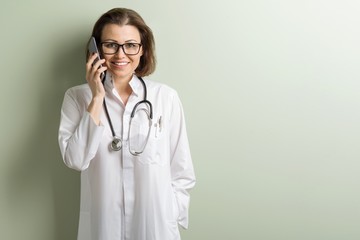 Positive doctor woman talking mobile phone.