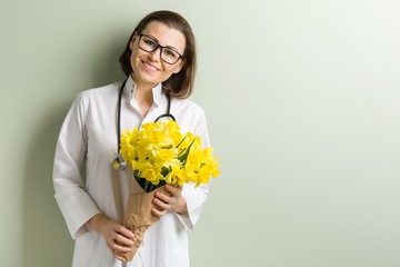 Smiling woman doctor with bouquet of flowers.