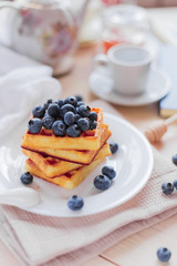 Belgian waffles with blueberries on the light wooden table. Healthy breakfast. 