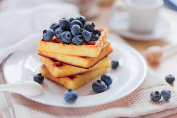 Belgian waffles with blueberries on the light wooden table. Healthy breakfast. 