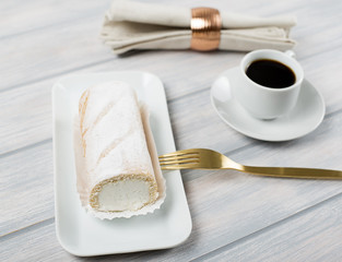 Cream pie served on tray next to coffee, fork and napkin on wooden table. Food
