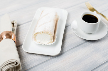 Cream pie served on tray next to coffee, fork and napkin on wooden table. Food
